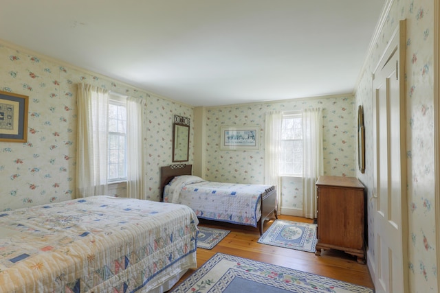 bedroom featuring wallpapered walls, hardwood / wood-style floors, and ornamental molding