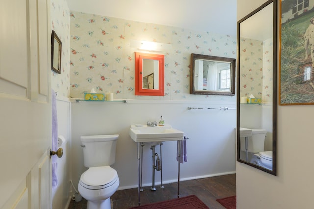 bathroom with wainscoting, wallpapered walls, wood finished floors, and toilet