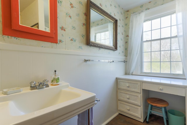 bathroom featuring wallpapered walls, a sink, and a wealth of natural light