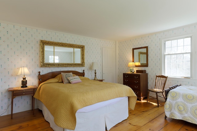 bedroom featuring wood-type flooring, wallpapered walls, and ornamental molding