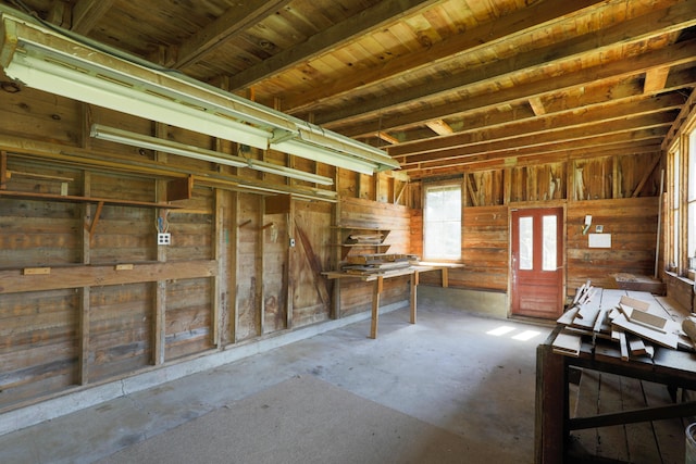miscellaneous room with wood walls and unfinished concrete flooring