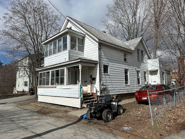view of front of house with fence and a sunroom
