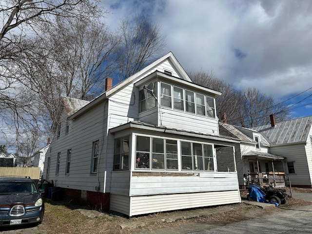 view of front facade with a sunroom and a chimney