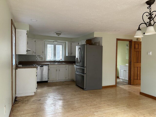 669 New Dam Rd, Waterboro, ME 04061 - kitchen with light wood-style floors, white cabinetry, dark countertops, stainless steel appliances, and baseboards