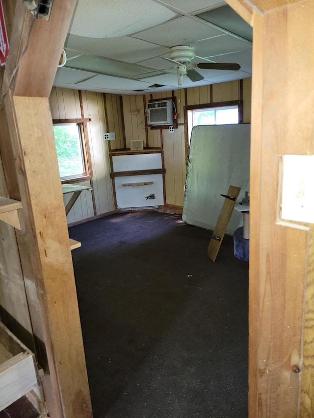 interior space featuring a wall mounted AC, dark carpet, and ceiling fan