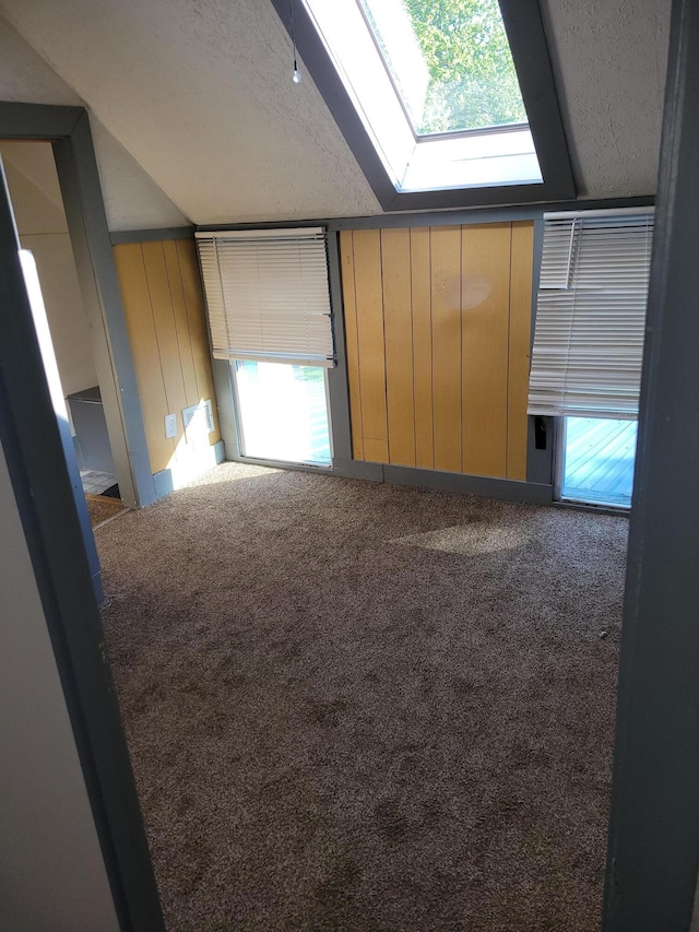unfurnished room with a skylight, carpet, and a textured ceiling