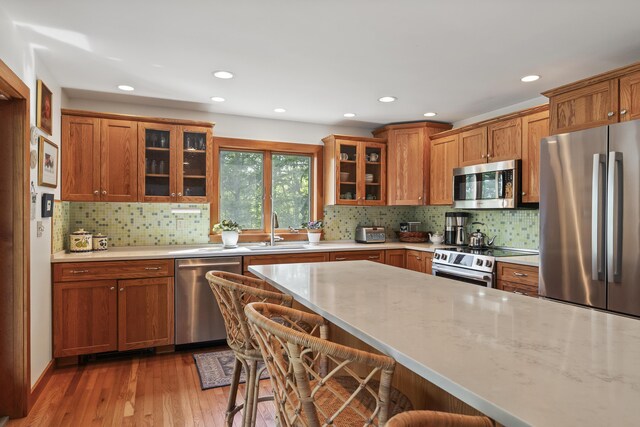 86 Firth Dr, Boothbay, ME 04537 - kitchen featuring appliances with stainless steel finishes, a sink, a kitchen breakfast bar, light wood-style floors, and brown cabinets