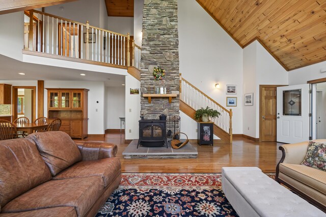 86 Firth Dr, Boothbay, ME 04537 - living room featuring stairway, a wood stove, wood finished floors, baseboards, and high vaulted ceiling