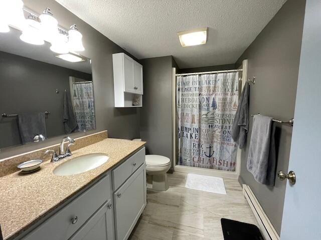 24 Clifford Rd Unit 18, Naples, ME 04055 - full bathroom with a shower with shower curtain, a baseboard heating unit, and toilet