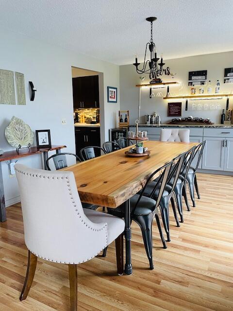 24 Clifford Rd Unit 18, Naples, ME 04055 - dining space with a textured ceiling, light wood-style flooring, and a notable chandelier