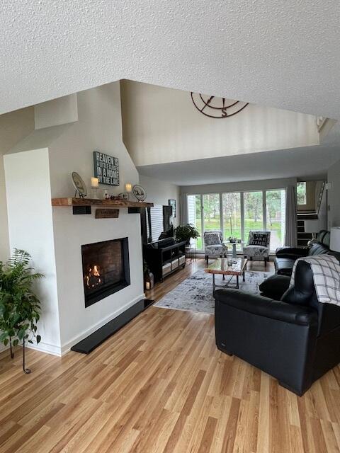 24 Clifford Rd Unit 18, Naples, ME 04055 - living room featuring a textured ceiling, light wood finished floors, and a lit fireplace