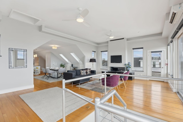 living area featuring a wall mounted AC, baseboards, hardwood / wood-style floors, and ceiling fan