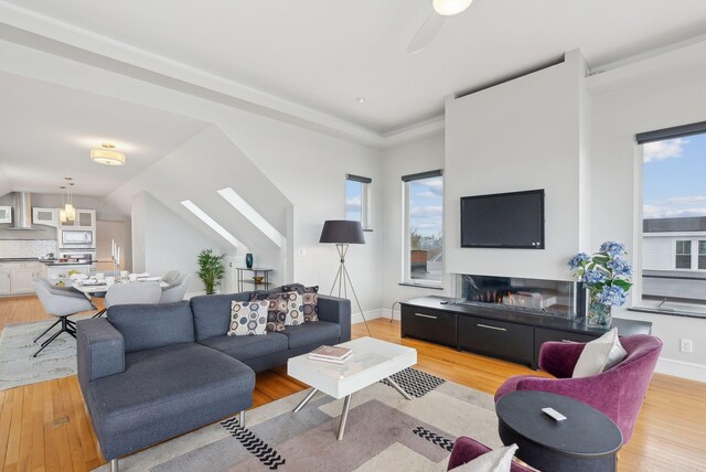 living area featuring light wood finished floors, baseboards, and ceiling fan