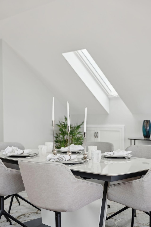 dining space with vaulted ceiling with skylight