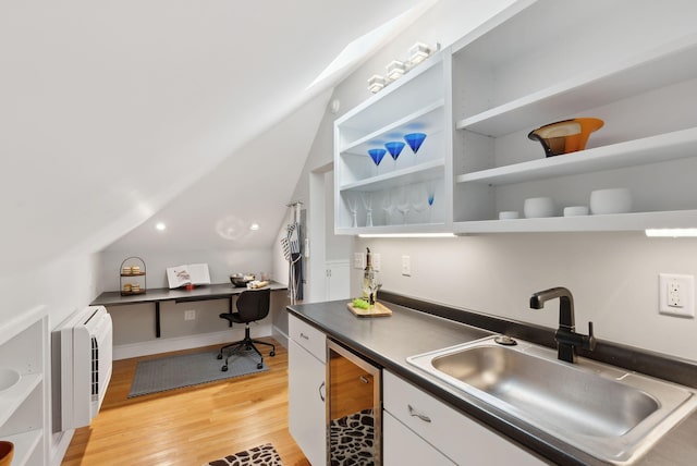 kitchen featuring open shelves, dark countertops, white cabinets, light wood finished floors, and a sink