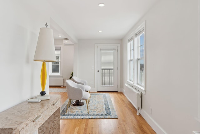 sitting room featuring baseboards, light wood-type flooring, radiator, and recessed lighting