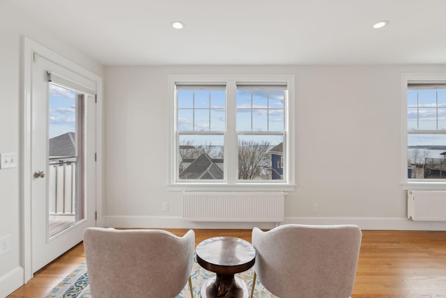 living area with radiator heating unit, recessed lighting, and light wood finished floors