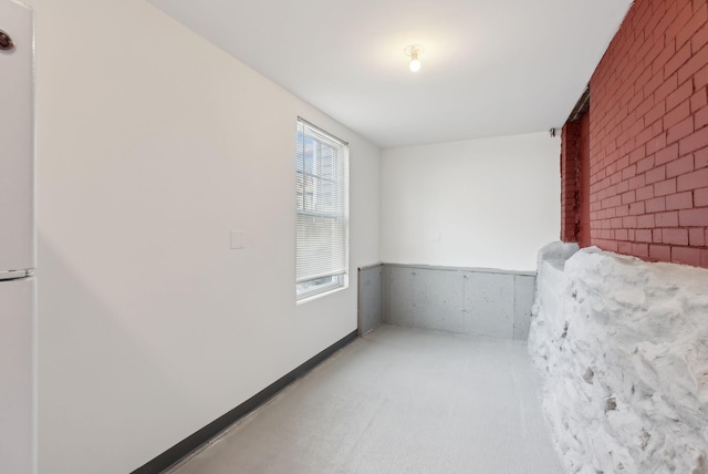 spare room with brick wall and carpet flooring