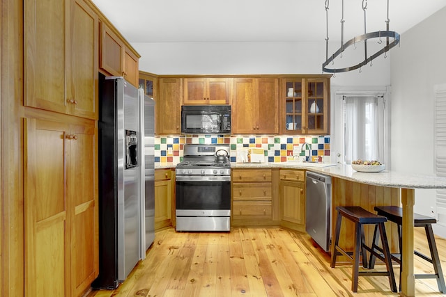 15 Obrion St Unit A, Portland, ME 04101 - kitchen with appliances with stainless steel finishes, glass insert cabinets, a peninsula, and light wood finished floors