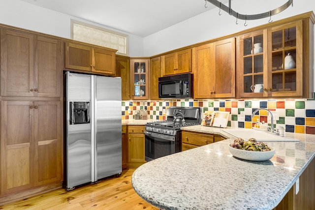 15 Obrion St Unit A, Portland, ME 04101 - kitchen with appliances with stainless steel finishes, a sink, brown cabinets, a peninsula, and backsplash