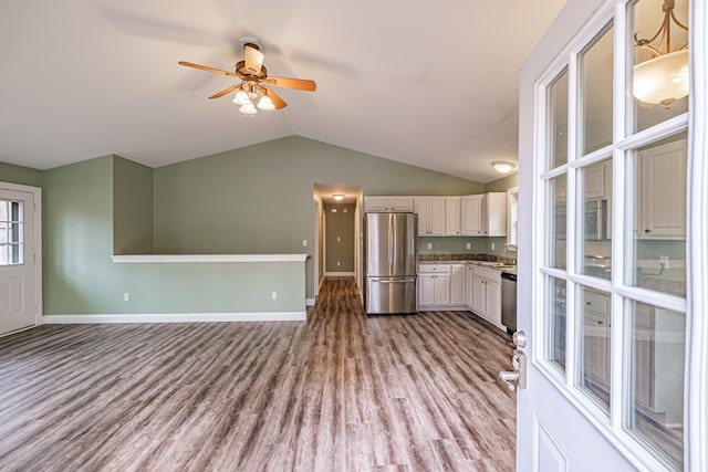 kitchen with stainless steel appliances, vaulted ceiling, baseboards, wood finished floors, and ceiling fan