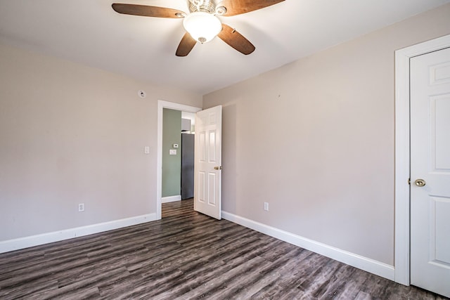 unfurnished bedroom featuring ceiling fan, baseboards, dark wood-style floors, and freestanding refrigerator