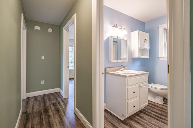 bathroom featuring baseboards, wood finished floors, vanity, and toilet