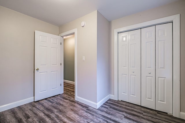 unfurnished bedroom featuring baseboards, a closet, and dark wood-style floors