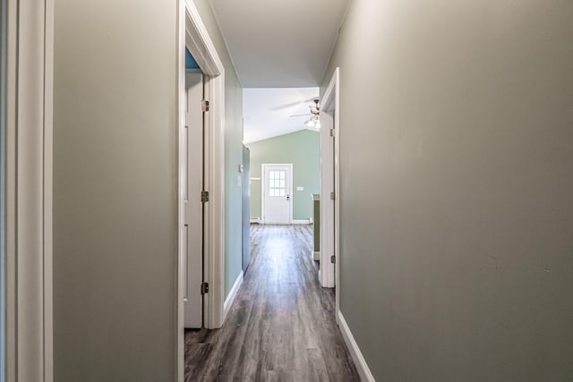 hall featuring vaulted ceiling, baseboards, and dark wood-style flooring