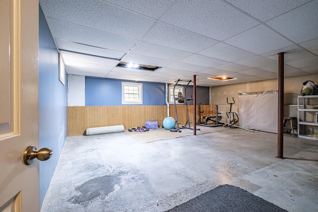 exercise area featuring wood walls, a wainscoted wall, and a paneled ceiling