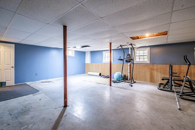 below grade area with wooden walls, a paneled ceiling, and a wainscoted wall