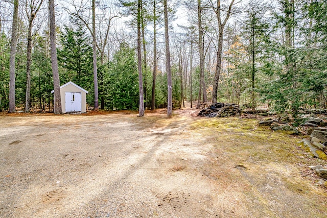 view of yard with a view of trees, an outbuilding, and a shed