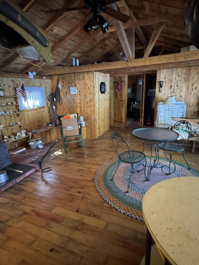 77 Orchard Dr, Saint Albans, ME 04971 - interior space featuring lofted ceiling with beams, a wood stove, wood walls, and hardwood / wood-style floors