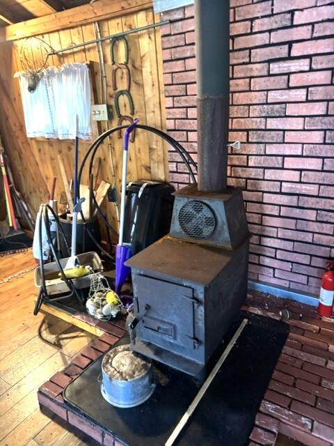 77 Orchard Dr, Saint Albans, ME 04971 - room details with a wood stove, wood finished floors, wood walls, and a fire extinguisher