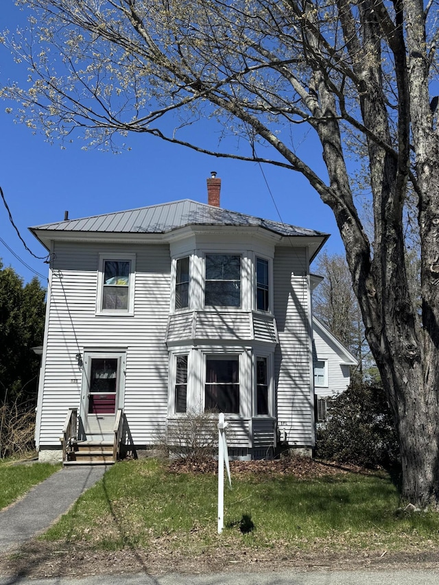 131 George St, Pittsfield, ME 04967 - view of front facade featuring metal roof, entry steps, a front lawn, and a chimney