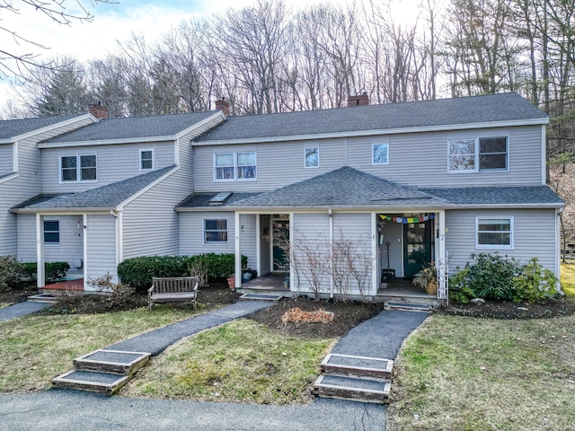 view of front of property featuring roof with shingles, a front lawn, and a porch