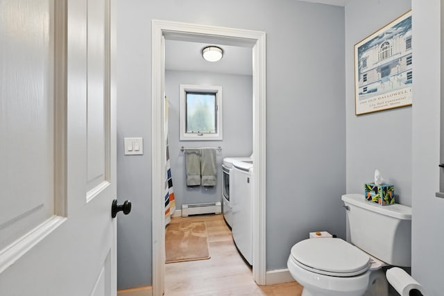 full bathroom with a baseboard heating unit, washer and clothes dryer, toilet, and wood finished floors