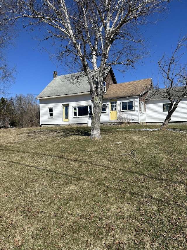 back of house with a chimney and a yard