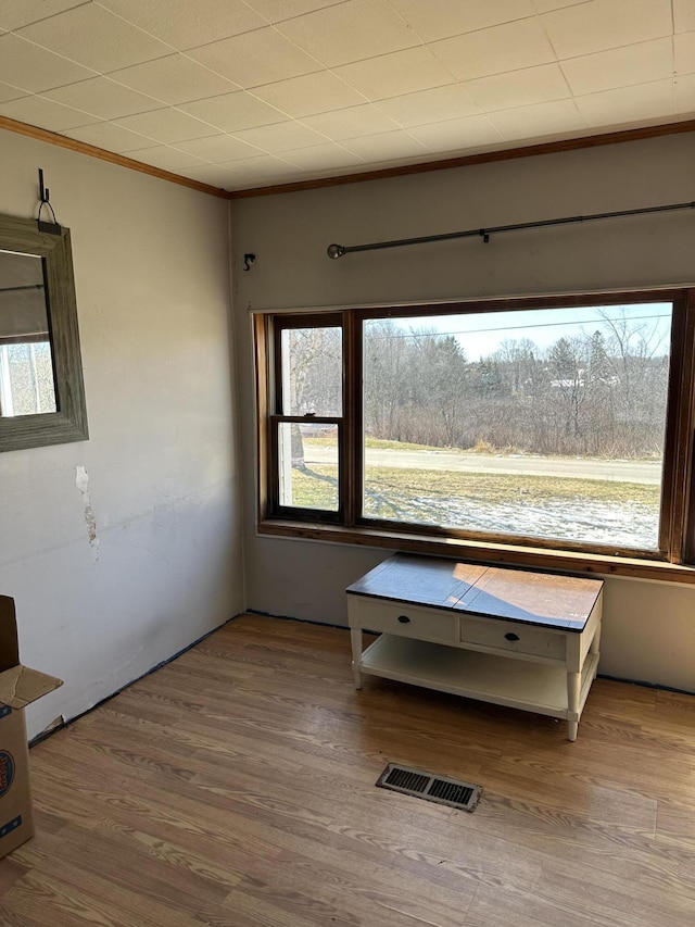 unfurnished room featuring wood finished floors, visible vents, and ornamental molding