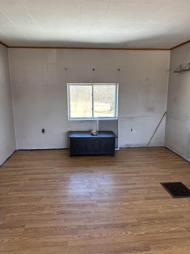 spare room featuring wood finished floors, visible vents, and ornamental molding