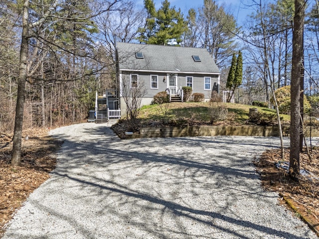 new england style home with driveway and roof with shingles