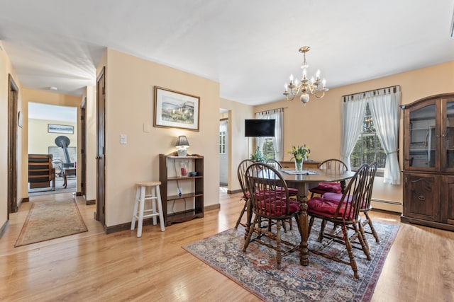 dining space featuring a baseboard heating unit, light wood-style floors, and a notable chandelier