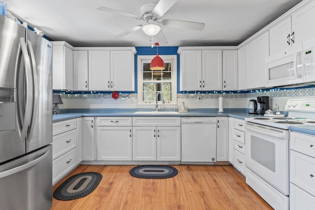 kitchen featuring tasteful backsplash, a sink, white appliances, light wood finished floors, and white cabinets