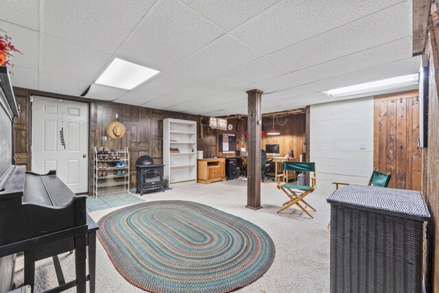 interior space with a paneled ceiling, a wood stove, and wood walls