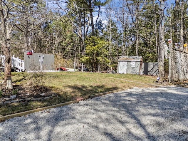 view of yard featuring an outdoor structure, a storage unit, and fence
