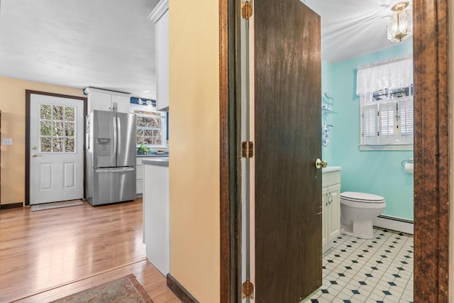 bathroom with a baseboard heating unit, wood finished floors, and toilet