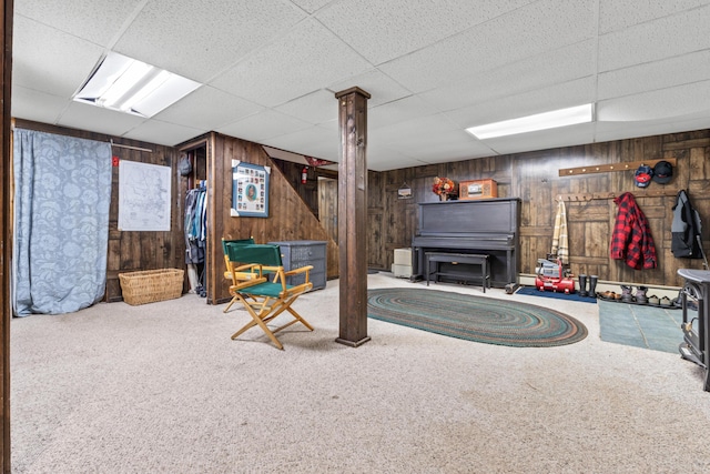 interior space featuring a baseboard heating unit, carpet flooring, wood walls, and a drop ceiling