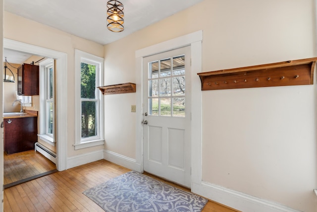 entryway with a baseboard radiator, light wood-style flooring, a healthy amount of sunlight, and baseboards
