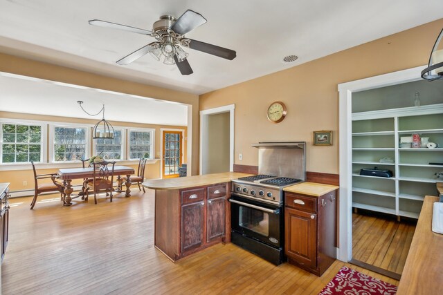 kitchen with stainless steel gas range oven, light countertops, light wood-style floors, a peninsula, and ceiling fan