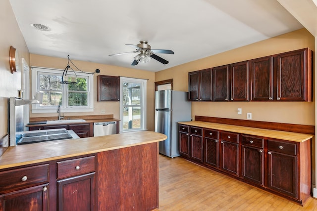 kitchen featuring wood counters, appliances with stainless steel finishes, light wood-style floors, and a sink